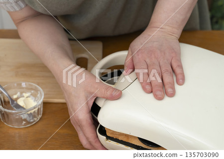 Hands making a hot sandwich with a hot sandwich maker Hands making a hot sandwich with a hot sandwich maker 135703090