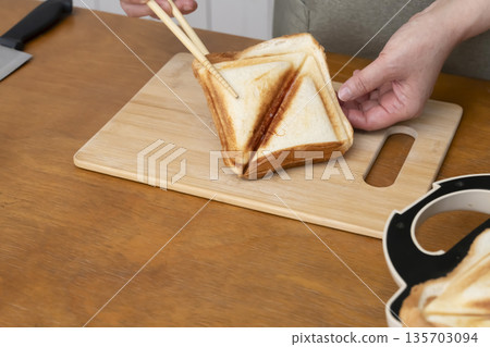 Hands making a hot sandwich with a hot sandwich maker Hands making a hot sandwich with a hot sandwich maker 135703094