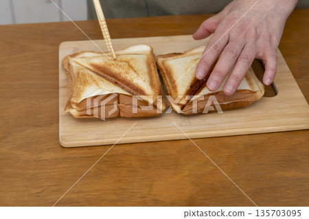 Hands making a hot sandwich with a hot sandwich maker 135703095