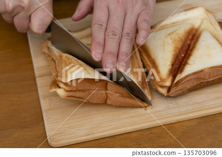 Hands making a hot sandwich with a hot sandwich maker 135703096