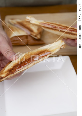 Hands making a hot sandwich with a hot sandwich maker Hands making a hot sandwich with a hot sandwich maker 135703098