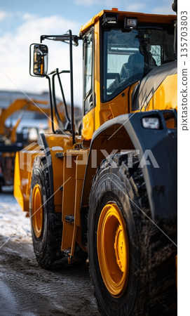 Heavy machinery works on a construction site during daylight in a snowy environment with multiple vehicles present Heavy machinery works on a construction site during daylight in a snowy environment with multiple vehicles present 135703803