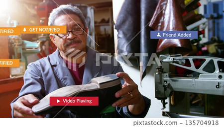 Inspecting senior cobbler turning black shoe sole at workbench inside repair workshop, with tools Inspecting senior cobbler turning black shoe sole at workbench inside repair workshop, with tools 135704918
