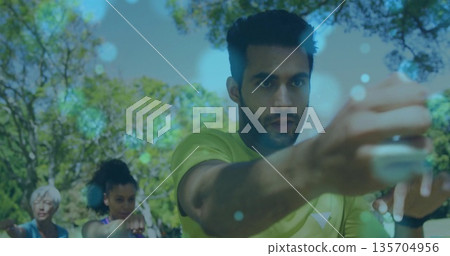 Punching adult Indian man wearing neon green shirt and smartwatch, in leafy park fitness class Punching adult Indian man wearing neon green shirt and smartwatch, in leafy park fitness class 135704956