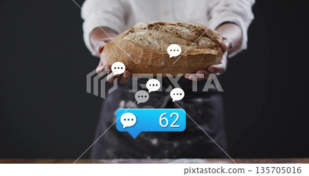 Holding artisanal loaf, baker wearing apron in bakery, displaying chat bubbles and comment count 62 135705016