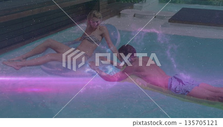 Man and woman floating and reaching hands in backyard pool, with transparent ring and yellow float Man and woman floating and reaching hands in backyard pool, with transparent ring and yellow float 135705121