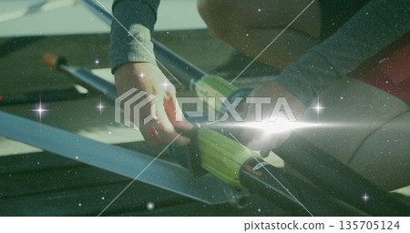 Securing athlete fastening carbon-fiber oars into oarlocks on dock, wearing grey top and red shorts 135705124