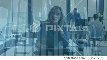 Tapping digital tablet, office woman working in open-plan office, with keyboard, coffee cup 135705145