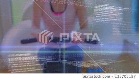 Woman in sportswear gripping rowing handlebar, rowing at fitness studio with digital code overlay Woman in sportswear gripping rowing handlebar, rowing at fitness studio with digital code overlay 135705187