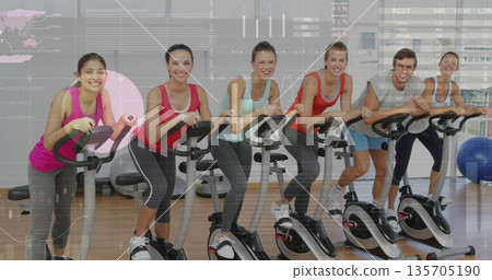 Pedaling group of six adults on stationary bikes in workout studio, with exercise ball Pedaling group of six adults on stationary bikes in workout studio, with exercise ball 135705190