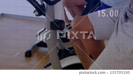 Pedaling adult man in shorts on bikes at fitness studio with display reading 15 Pedaling adult man in shorts on bikes at fitness studio with display reading 15 135705193