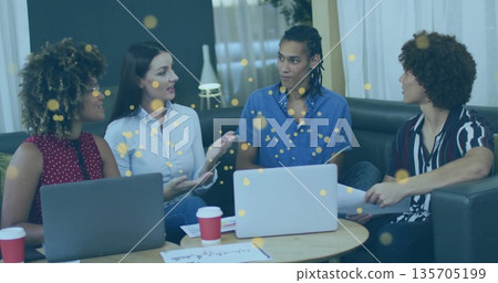Collaborating four-person office team meeting in casual lounge, with laptops and red coffee cups 135705199