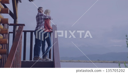 Standing couple in flannel, orange knit overlooking lake and mountains by cabin railing, copy space Standing couple in flannel, orange knit overlooking lake and mountains by cabin railing, copy space 135705202