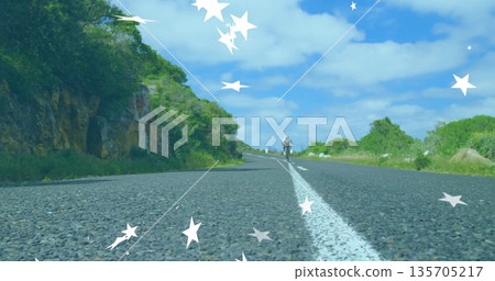 Riding cyclist wearing helmet on racing bike along centerline on rural road, with digital stars 135705217