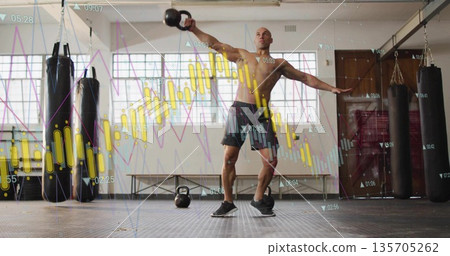 Swinging kettlebell shirtless athlete performing exercise in gym with punching bags, chart overlay 135705262