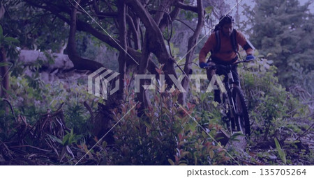 Riding mountain biker wearing orange jersey on forest trail with water pack and helmet, copy space Riding mountain biker wearing orange jersey on forest trail with water pack and helmet, copy space 135705264