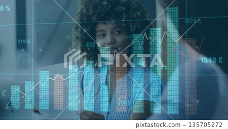 Curly-haired professional reviewing financial data overlays in modern office, with tablet 135705272