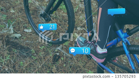 Riding cyclist pedaling over forest floor trail, with blue bike frame and social media icons 135705293
