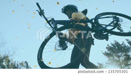 Hoisting cyclist lifting mountain bike overhead on trail, wearing reflective leggings and helmet 135705301