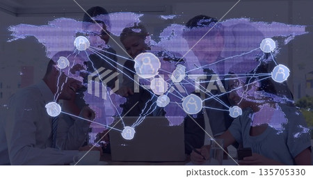 Team in business attire collaborating in meeting room pointing at laptop, notebooks and world map 135705330