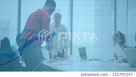 Collaborating professionals leaning over conference table in office, with laptops and documents 135705347