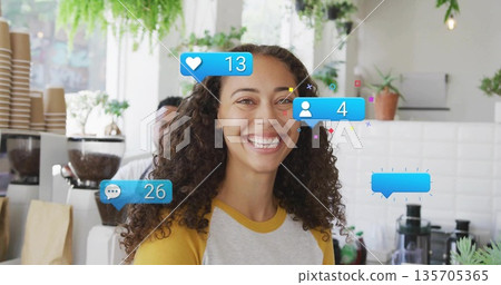 Smiling woman wearing baseball tee working at coffee shop counter, with social media graphics 135705365