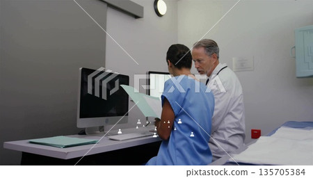 Reviewing nurse and doctor consulting patient charts in clinic exam room, with computer monitors Reviewing nurse and doctor consulting patient charts in clinic exam room, with computer monitors 135705384