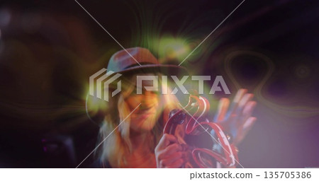 Playing female musician holding tambourine, performing on dimly lit stage with swirling lights Playing female musician holding tambourine, performing on dimly lit stage with swirling lights 135705386
