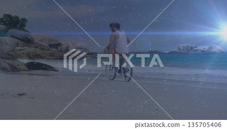 Cycling couple wearing beachwear on beach cruiser bicycle along sandy shoreline, with sunlight Cycling couple wearing beachwear on beach cruiser bicycle along sandy shoreline, with sunlight 135705406