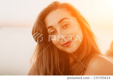 Woman portrait sunset captures a smiling young female at golden hour outdoors enjoying a peaceful evening atmosphere by the sea Woman portrait sunset captures a smiling young female at golden hour outdoors enjoying a peaceful evening atmosphere by the sea 135705614