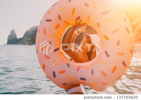 Woman, donut, sea. Happy woman with donut inflatable ring enjoying summer holiday at sea. 135705620