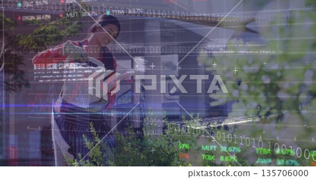 Watering shrubs woman wearing apron with metal watering can in front yard, with financial overlay Watering shrubs woman wearing apron with metal watering can in front yard, with financial overlay 135706000
