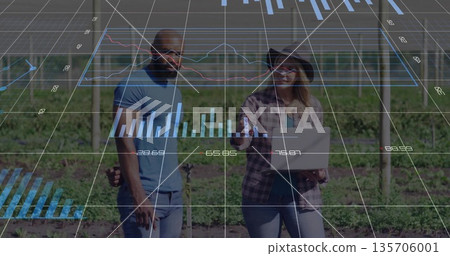 Analyzing colleagues monitoring grape vines in vineyard, with laptop, posts and wires, data overlay 135706001