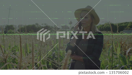 Holding smartphone to ear farmer wearing straw hat in cornfield under data overlay, copy space 135706002