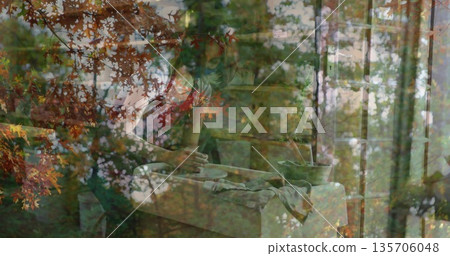 Potter wearing grey apron shaping bowl on spinning wheel in workshop, autumn leaves overlay Potter wearing grey apron shaping bowl on spinning wheel in workshop, autumn leaves overlay 135706048