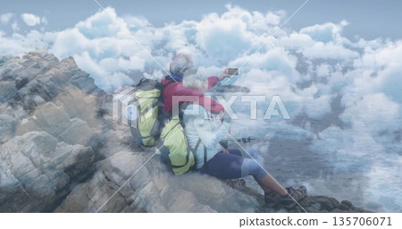 Taking selfie mature hiking couple leaning on coastal edge, with smartphone, backpacks and poles Taking selfie mature hiking couple leaning on coastal edge, with smartphone, backpacks and poles 135706071