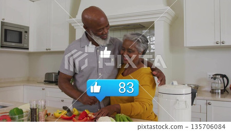 Mature couple chopping peppers and tomatoes on cutting board in home kitchen, with rice cooker Mature couple chopping peppers and tomatoes on cutting board in home kitchen, with rice cooker 135706084