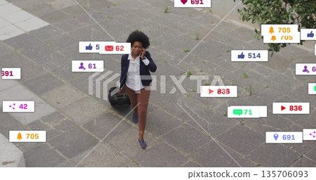 Walking woman in suit carrying suitcase and talking on smartphone in plaza, with notification icons Walking woman in suit carrying suitcase and talking on smartphone in plaza, with notification icons 135706093