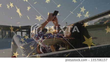 Resting woman wearing plaid shirt and jeans using smartphone at skate ramp with skateboard, railing Resting woman wearing plaid shirt and jeans using smartphone at skate ramp with skateboard, railing 135706157