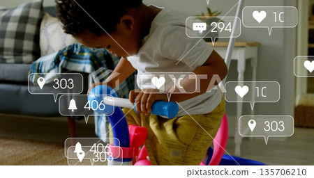 Riding toddler wearing yellow pants on blue ride-on toy in living room, with social icons 135706210