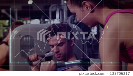 Male trainee wearing sportswear pushing chest press machine in gym, with performance graph overlay 135706217