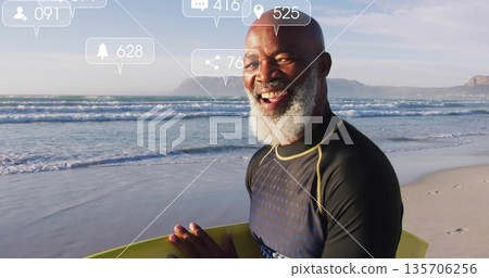 Smiling wetsuit-clad surfer holding yellow surfboard at shoreline, with social icons, copy space 135706256