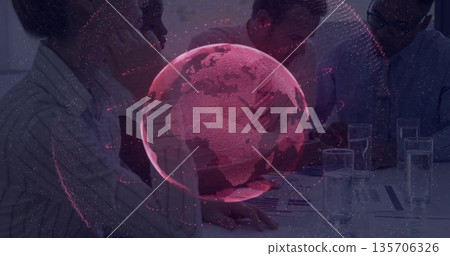 Projecting red holographic globe above table, business-casual colleagues reviewing reports Projecting red holographic globe above table, business-casual colleagues reviewing reports 135706326