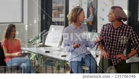 Gesturing mid adult woman discussing project with male colleague in modern office, featuring tablet 135706346