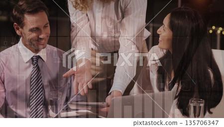 Reviewing digital charts, business professionals leaning over conference table, pointing at tablet Reviewing digital charts, business professionals leaning over conference table, pointing at tablet 135706347