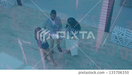 Three executives reviewing market metrics in office lobby, with tablet clipboard notebook papers 135706350