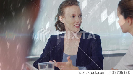 Speaking businesswoman gesturing toward colleague in conference room, with water glass and overlays Speaking businesswoman gesturing toward colleague in conference room, with water glass and overlays 135706358