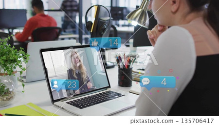 Office worker focusing on laptop call with floating notifications at desk with lamp, copy space Office worker focusing on laptop call with floating notifications at desk with lamp, copy space 135706417