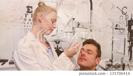 Female optometrist applying eye drops and examining male patient in exam room, with phoropter Female optometrist applying eye drops and examining male patient in exam room, with phoropter 135706419