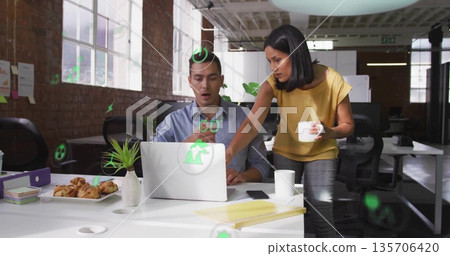 Collaborating pair reviewing green digital icons on laptop in modern loft office, with ceramic mugs Collaborating pair reviewing green digital icons on laptop in modern loft office, with ceramic mugs 135706420